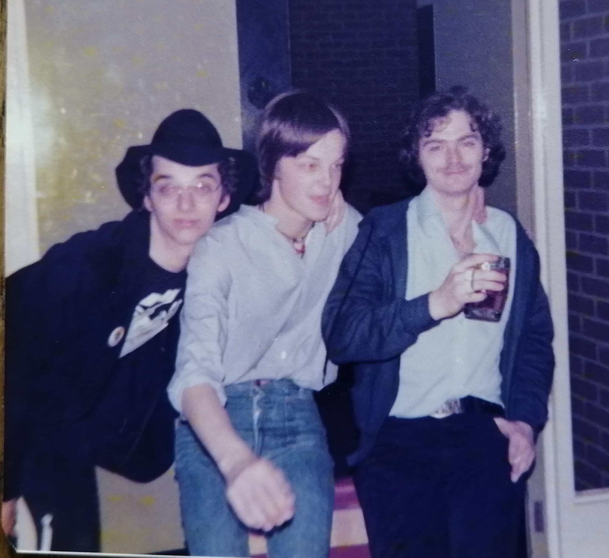 Three young men pose together. 