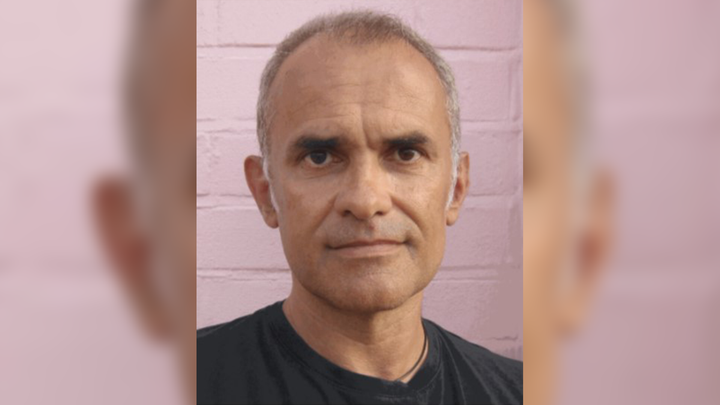 A portrait of Adrian Hart is shown against a backdrop of a pastel-pink brickwall.