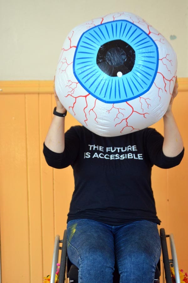A Very Queer Nazi Faust participant holding a giant eyeball with the words ’The Future is Accessible’ on her shirt. Photo by Ann Nicholls.